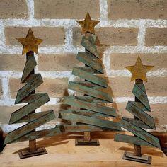 three wooden christmas trees with gold stars on them, sitting in front of a brick wall