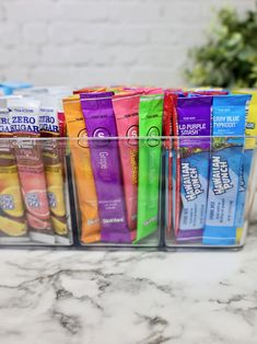 a plastic container filled with lots of different types of snacks and candy bar wrappers on top of a marble counter