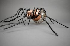 a close up of a metal spider on a white surface with black and silver wires