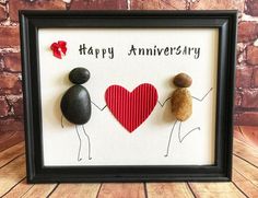 two rocks holding hands with the words happy anniversary written on them in front of a frame