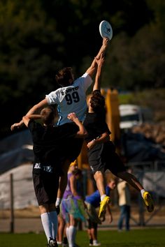 two men jumping in the air to catch a frisbee while others look on