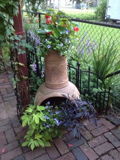 a potted planter sitting on top of a brick walkway next to a fence