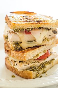 a grilled cheese sandwich is stacked on top of each other with pesto and tomatoes