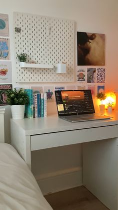 a laptop computer sitting on top of a white desk next to a lamp and books