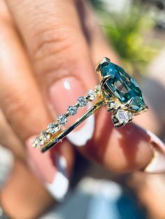 a woman's hand holding an emerald and diamond ring