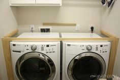 a washer and dryer in a small room with white cabinets on the wall