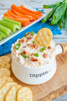 a bowl filled with dip surrounded by crackers and celery