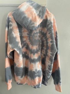 an orange and grey tie dye hoodie hanging on a wall