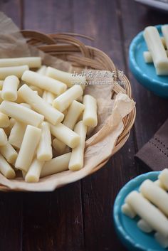 several pieces of cheese sitting in a basket on a wooden table next to other plates