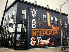 an image of a building that is painted black and orange with the words wild independent & proud on it