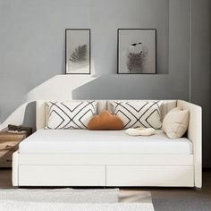 a living room with a white couch and two framed pictures on the wall above it