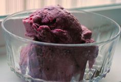 a bowl filled with purple ice cream next to a window