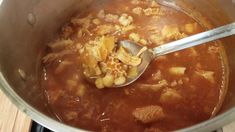 a ladle full of food is being stirred by a spoon in a pot on the stove