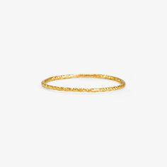 the thin gold ring with textured details on it, sitting against a white background