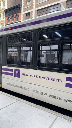 a purple and white bus is parked on the side of the street in front of some buildings