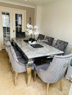 a dining room table with grey chairs around it