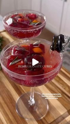 two glasses filled with liquid sitting on top of a wooden table next to each other