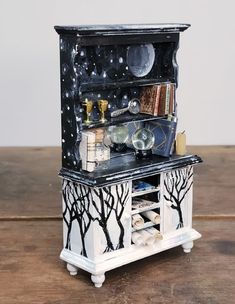 an old fashioned cabinet is decorated with black and white paint on the doors, drawers, and shelves