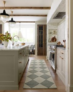 a kitchen with an area rug on the floor and cabinets in front of the sink