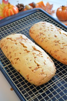 two loaves of bread sitting on top of a cooling rack next to pumpkins