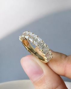 a person holding a gold ring with three baguettes on it's side