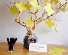 a vase filled with yellow paper hearts next to a tree