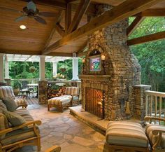 an outdoor living area with stone fireplace and seating