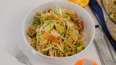 a white bowl filled with food next to an orange and silver fork on top of a table