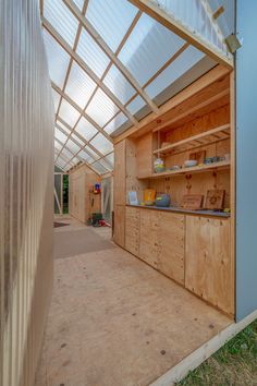 the inside of a building with wooden walls and shelves on each side, in front of a glass roof