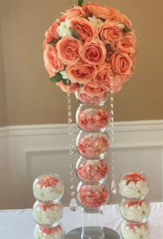 a tall vase filled with lots of pink flowers on top of a white table cloth