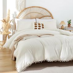 a bed with white linens and pillows in a bright room, next to a wicker headboard