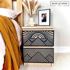 a black and white chest of drawers next to a bed with an orange blanket on it