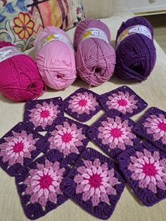 several balls of yarn sitting on top of a bed next to crocheted squares