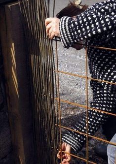 a woman is holding onto the bars of a fence