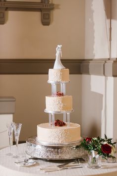 a wedding cake sitting on top of a table next to wine glasses and utensils