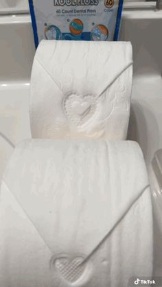 a close up of two folded towels in a bathtub with a box of tissues behind it