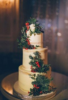 a three tiered wedding cake with berries and greenery