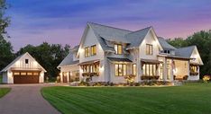 a large white house with lots of windows on the front and side of it at dusk