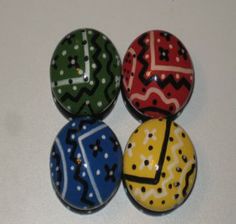 four different colored glass knobs with designs on them, all lined up in a row