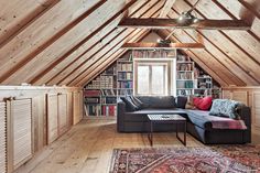 a living room filled with furniture and bookshelves in a wooden ceilinged area