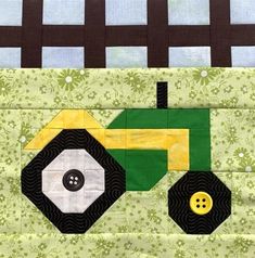 a piece of quilted fabric with a tractor on it's side and green flowers in the background