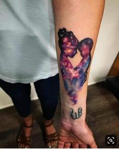 a woman's arm with a tattoo on it that has an image of two people in the shape of a heart