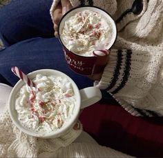 two cups of hot chocolate with whipped cream and candy canes