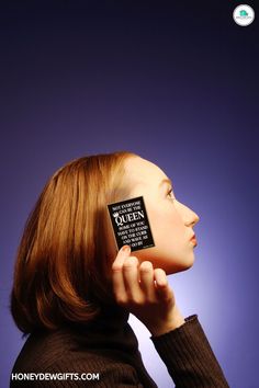 a woman holding up a piece of paper with the word queen on it in front of her face