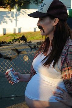 a pregnant woman wearing a hat and holding a can