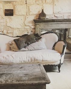 a white couch sitting in front of a fireplace next to a wooden table with two pillows on it