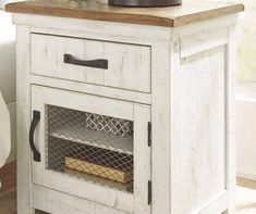 an old white cabinet with a drawer on the bottom and a shelf above it that has a basket full of flowers sitting on top