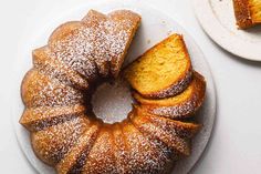 a bundt cake on a plate with powdered sugar and two plates next to it