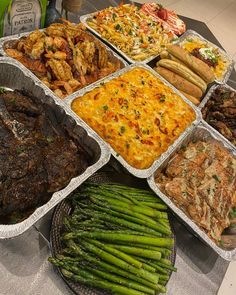 a table topped with trays of food next to green beans and asparagus