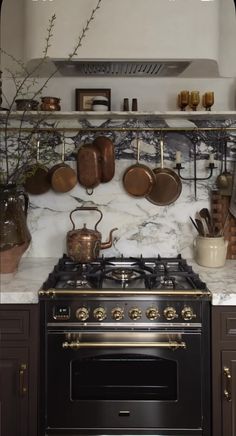 a stove top oven sitting inside of a kitchen next to a shelf filled with pots and pans